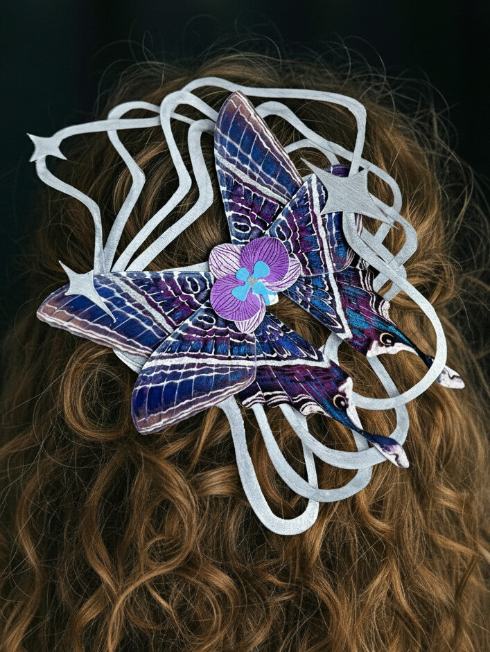 Moon Ripple, Fantasy Paper Moth Based on Moon Eyetail Moth, Decorative hair clip with purple butterfly design on a person's hair against a dark background