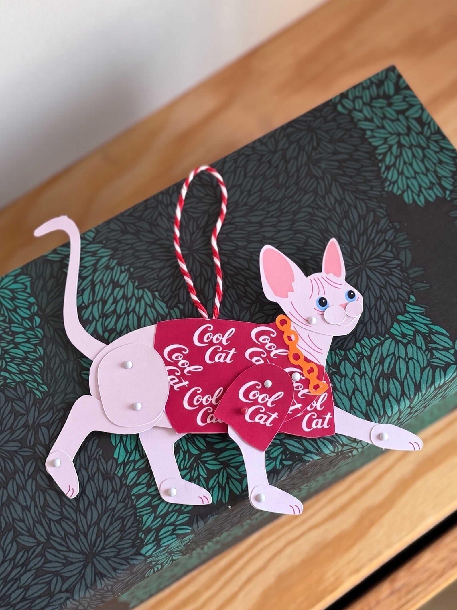 Sphynx in Red Shirt Paper Doll on a green leaf-patterned box